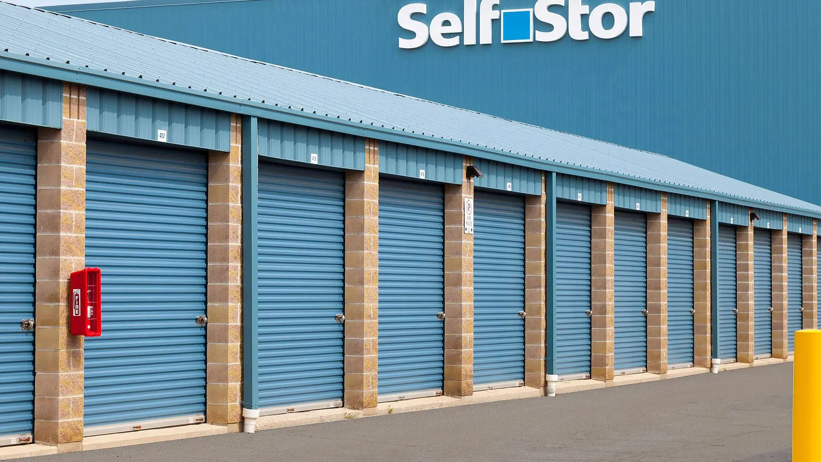Row of roll-up storage unit doors at a single-storey self-storage facility